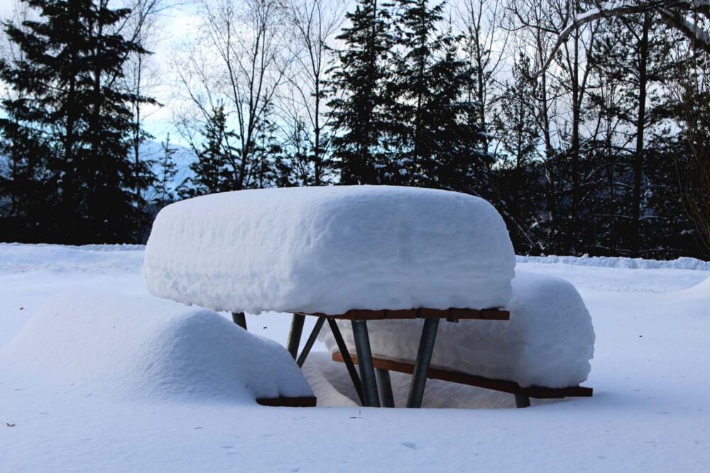 表面和长凳上有大量积雪的野餐桌