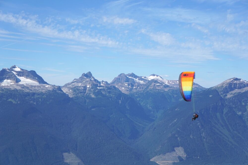 彩色滑翔伞在山脉前飞行