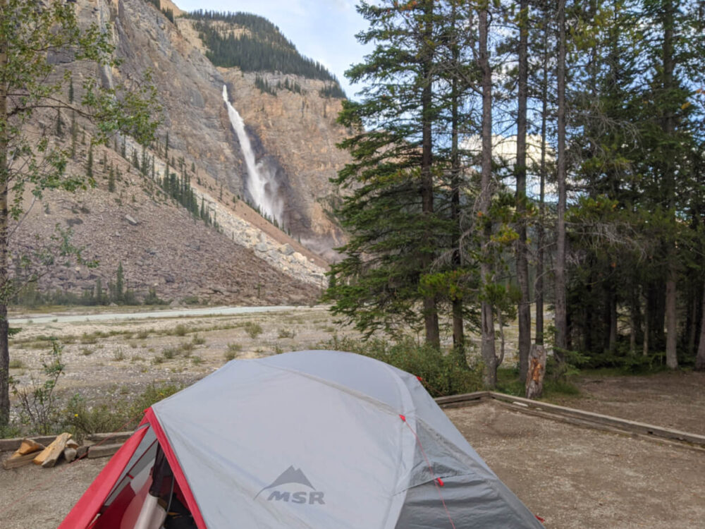 在巨大的瀑布前搭起帐篷，右手边是树