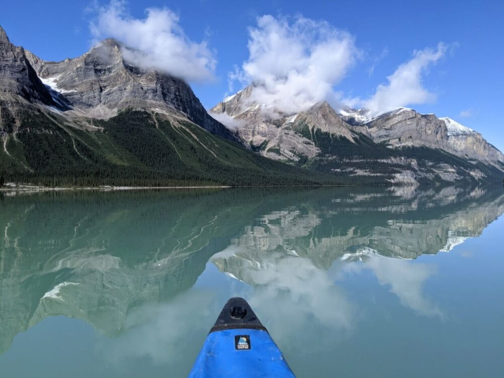独木舟的景色的恶性湖，与镜子般的倒影，大山脉在平静的表面