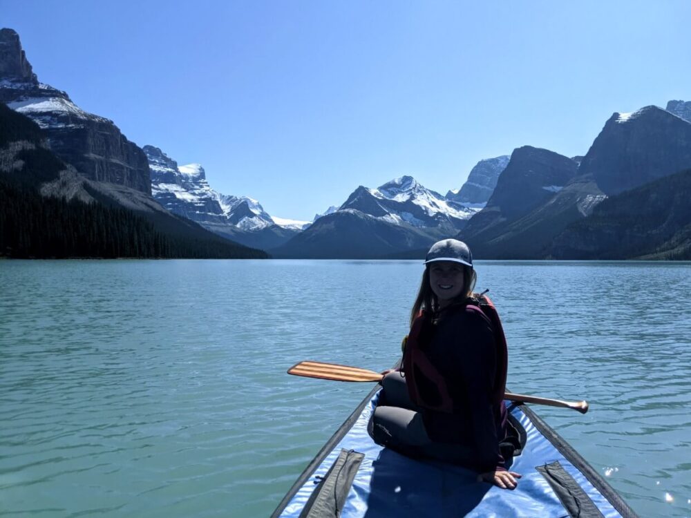 杰玛坐在独木舟的前面，以山为背景