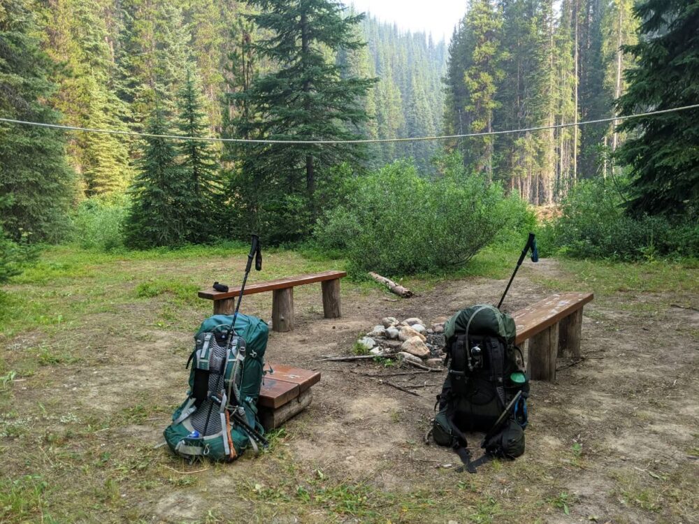 在被森林包围的马守卫营地，两个背包被支在火坑座位旁边