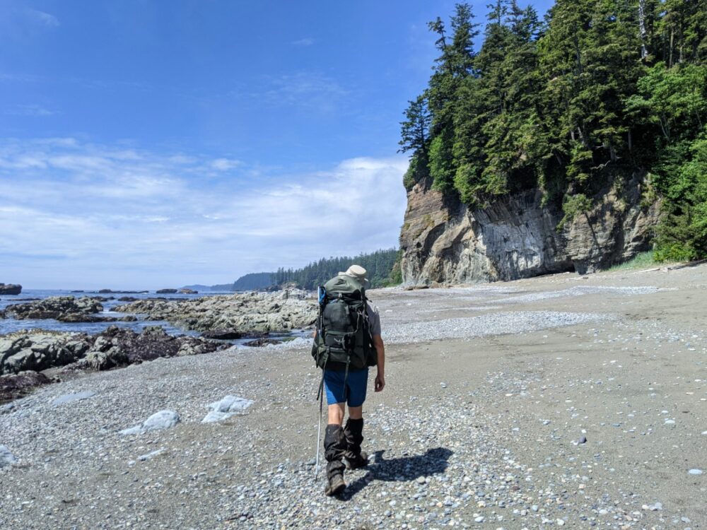 JR在海滩徒步旅行的后景，右边是高高的悬崖，左边是海洋