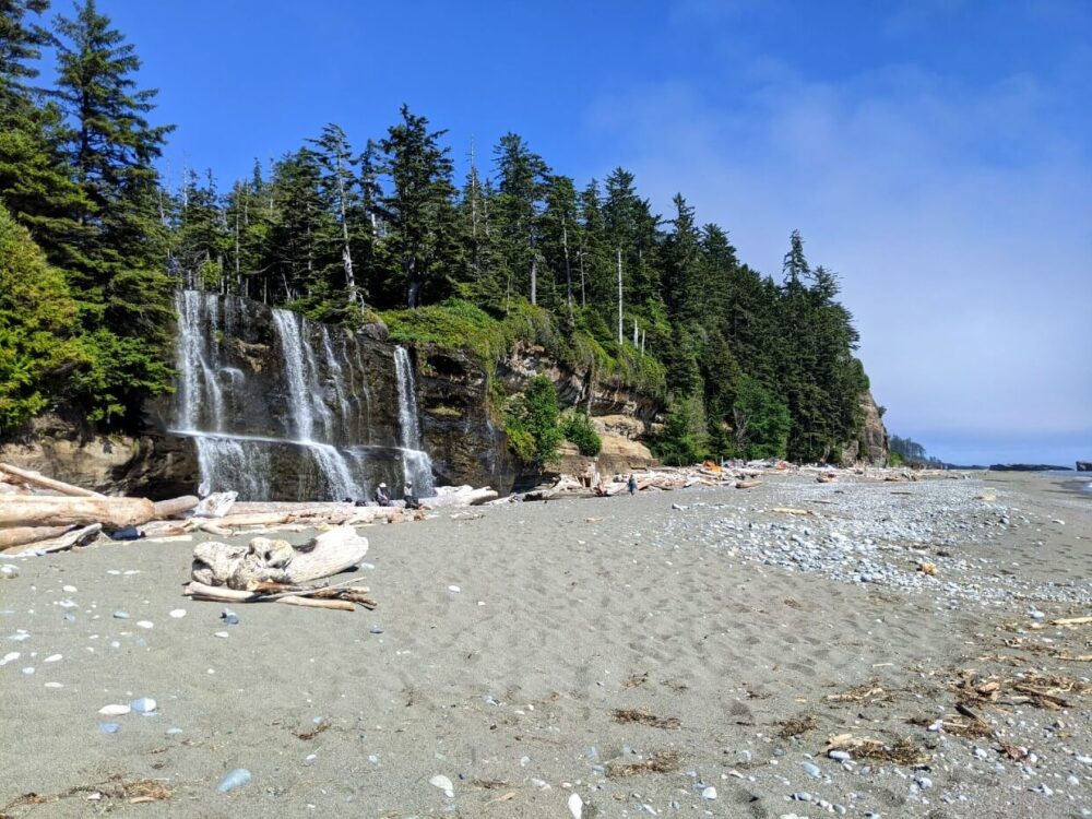 穿过海滩，左边是巨大的瀑布，远处是露营区