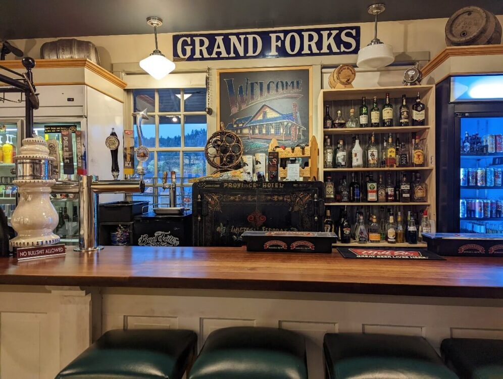 大叉子站酒吧内部木制酒吧，历史上的保险箱后面，架子上的酒精，铁路标志附近的天花板和啤酒冰箱