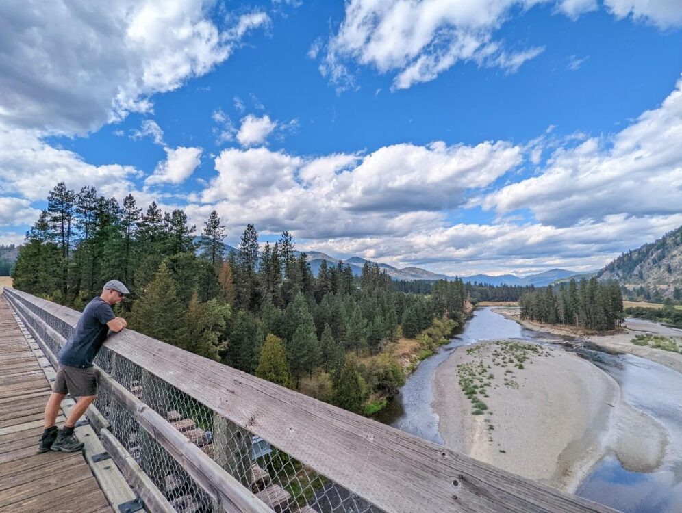 JR靠在木栈桥上，俯视着被群山环绕的宽阔的江盆