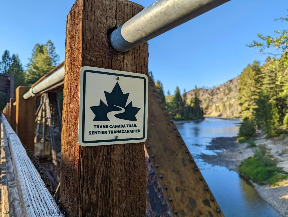 特写的跨加拿大步道标志在凯特尔河栈桥，与河流可见的背景