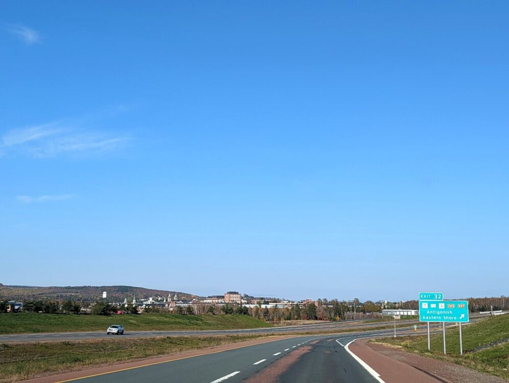 面向高速公路和对面的安提戈尼什镇的车辆视图。右边有一个绿色的路标，上面写着“安提戈尼什，东岸”，上面有一个箭头