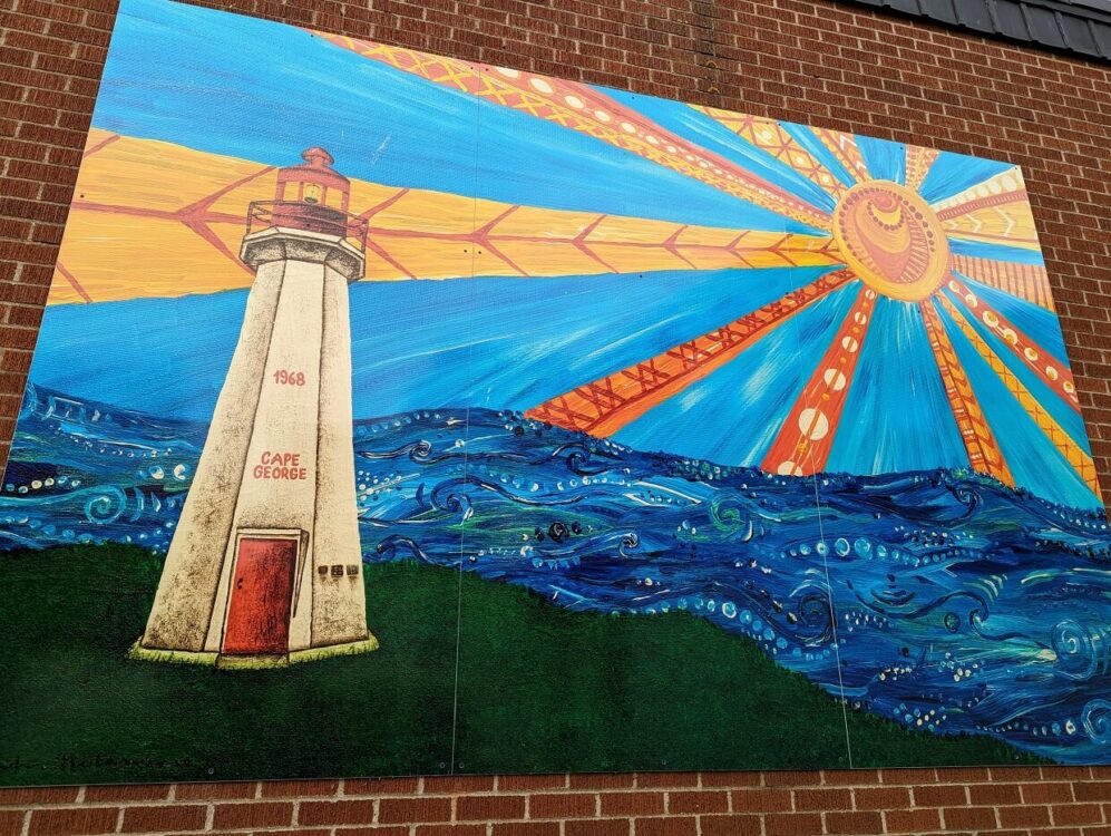 安提戈尼什市中心的灯塔壁画，贴在砖墙上。这幅壁画以红白相间的乔治角灯塔为特色，背景是大海上的大太阳