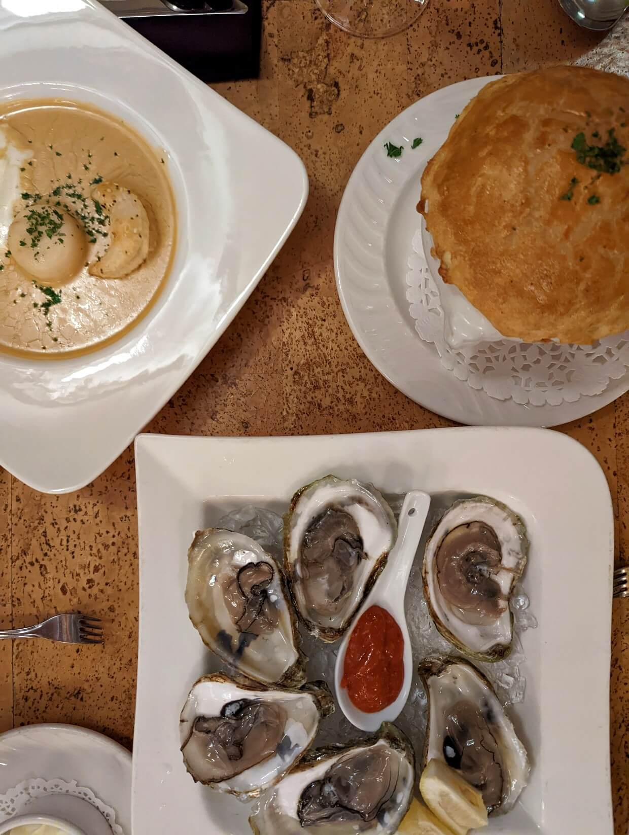 加布里奥餐厅的三道菜俯视图，包括浅棕色龙虾浓汤，酥皮杂烩碗和半打冰生蚝