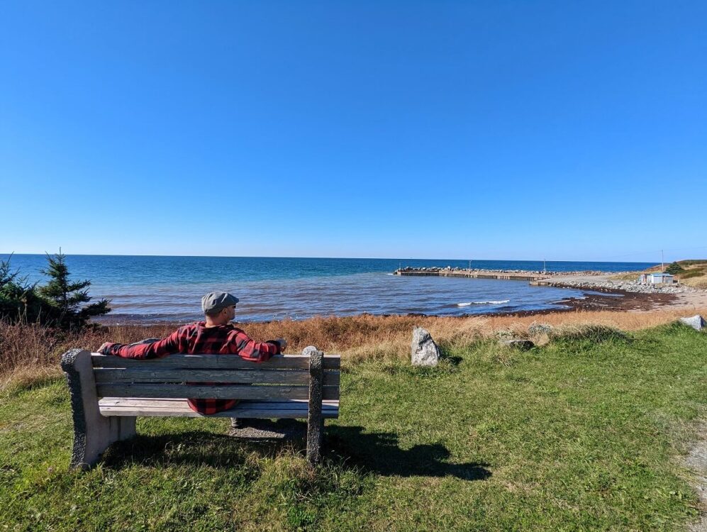 JR坐在长凳上的后景，望着小岩石湾与码头区域