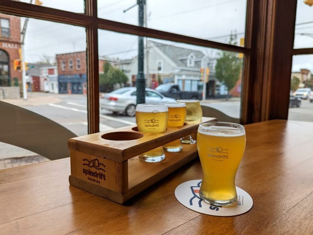 特写的精酿啤酒飞行在Spindrift啤酒厂，一种啤酒在垫子上更接近镜头。在背景中可以透过窗户看到移动的车辆
